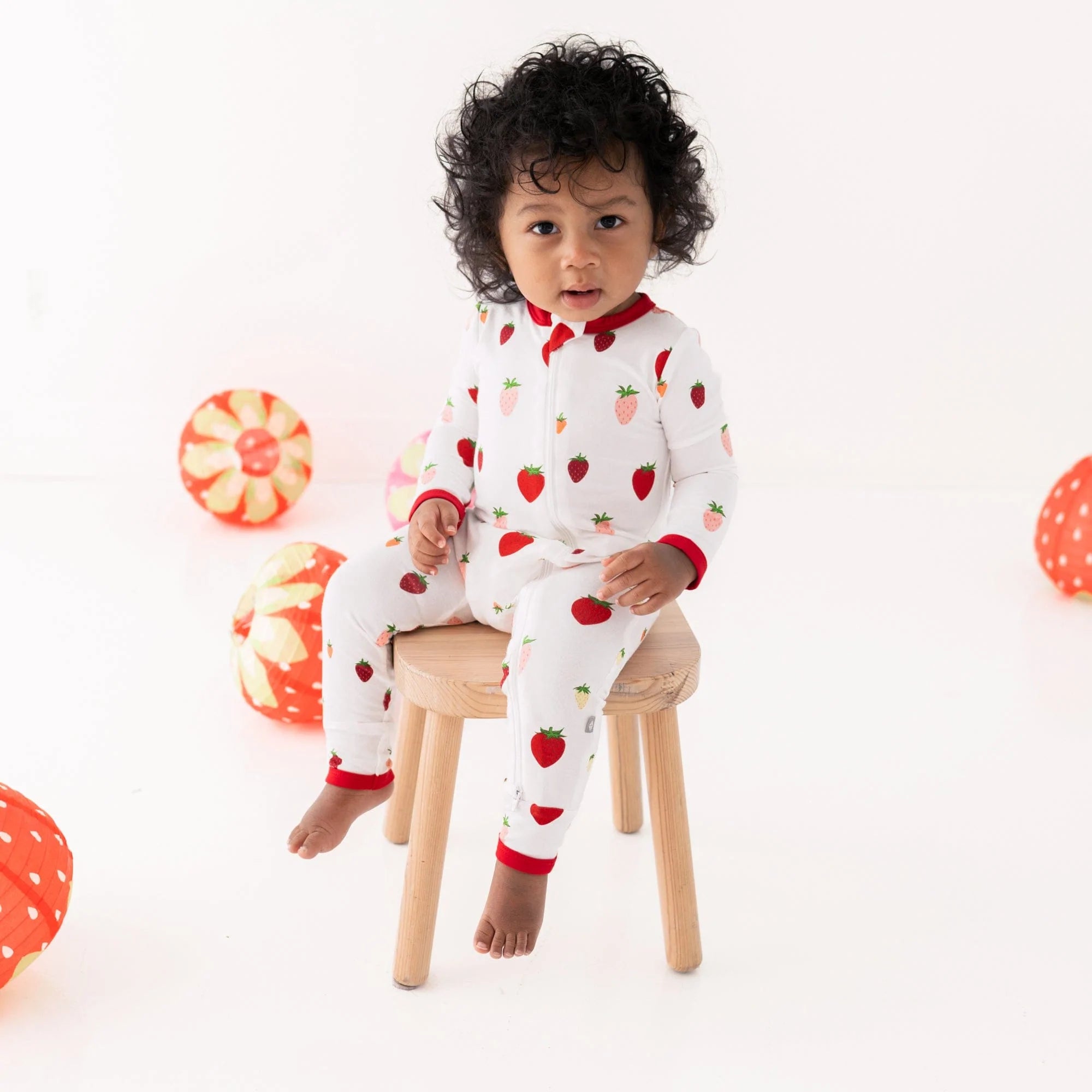 Toddler wearing Kyte Baby Strawberry patterned Zippered Romper